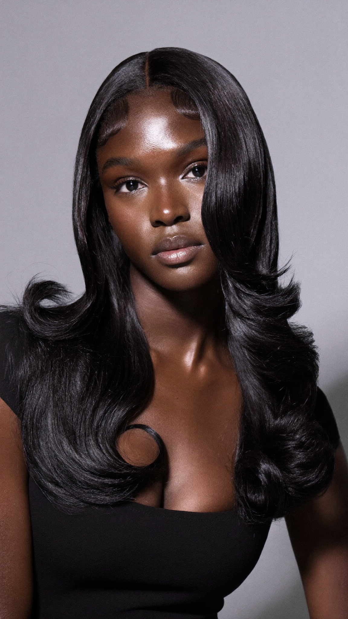 Glossy black hair with sleek face-framing layers and curled ends